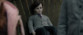 Movie still from “Brahms: The Boy II” (2020), directed by William Brent Bell – A doll sitting in a chair wearing a sweater and a tie; Close Up shot, High angle