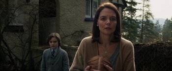 Movie still from “Brahms: The Boy II” (2020), directed by William Brent Bell – A woman and a boy are standing in front of a building; Close Up shot, Over the shoulder angle