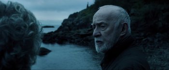 Movie still from “Brahms: The Boy II” (2020), directed by William Brent Bell – An older man standing in front of a body of water; Close Up shot, Low angle