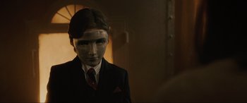 Movie still from “Brahms: The Boy II” (2020), directed by William Brent Bell – A man in a suit and tie wearing a mask; Close Up shot, Low angle