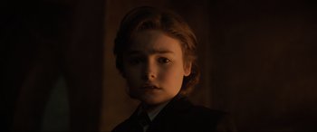 Movie still from “Brahms: The Boy II” (2020), directed by William Brent Bell – A boy in a suit and tie in a dimly lit room; Close Up shot, Low angle