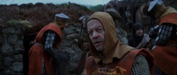 Movie still from “Braveheart” (1995), directed by Mel Gibson – An older man with a hooded jacket on; Close Up shot, Over the shoulder angle