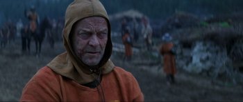 Movie still from “Braveheart” (1995), directed by Mel Gibson – An old man wearing an orange hooded sweatshirt; Close Up shot, Over the shoulder angle