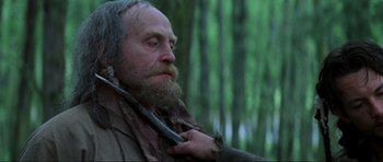 Movie still from “Braveheart” (1995), directed by Mel Gibson – An old man with a long beard holding a stick in his mouth; Close Up shot, Over the shoulder angle