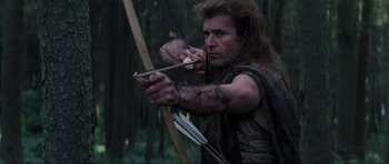 Movie still from “Braveheart” (1995), directed by Mel Gibson – A man with a bow and arrow in the woods; Medium shot, Low angle