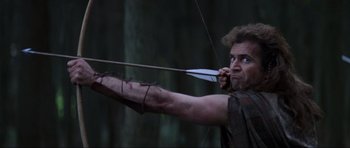 Movie still from “Braveheart” (1995), directed by Mel Gibson – A man is holding a bow and arrow in the woods; Medium shot, Low angle