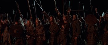 Movie still from “Braveheart” (1995), directed by Mel Gibson – A group of men in brown robes holding swords in the dark; Wide shot, Low angle