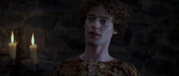 Movie still from “Braveheart” (1995), directed by Mel Gibson – A man with curly red hair wearing a brown and gold shirt; Close Up shot, Low angle