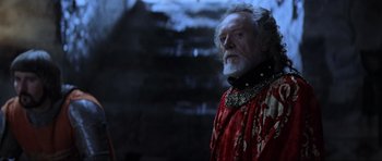 Movie still from “Braveheart” (1995), directed by Mel Gibson – An older man in a red and gold outfit; Close Up shot, Over the shoulder angle