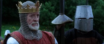 Movie still from “Braveheart” (1995), directed by Mel Gibson – An old man wearing a crown and holding a bell; Close Up shot, Low angle