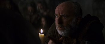 Movie still from “Braveheart” (1995), directed by Mel Gibson – An old man holding a lit candle in a dark room; Close Up shot, Over the shoulder angle