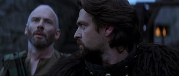 Movie still from “Braveheart” (1995), directed by Mel Gibson – A man with long hair and a beard is looking to his left; Close Up shot, Over the shoulder angle