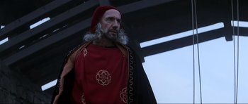 Movie still from “Braveheart” (1995), directed by Mel Gibson – A man with a beard wearing a red and black outfit; Close Up shot, Over the shoulder angle