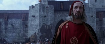 Movie still from “Braveheart” (1995), directed by Mel Gibson – A man dressed in medieval clothing standing in front of a castle; Close Up shot, Low angle