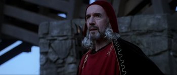 Movie still from “Braveheart” (1995), directed by Mel Gibson – An old man with a beard and a red robe; Close Up shot, Low angle