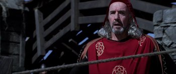 Movie still from “Braveheart” (1995), directed by Mel Gibson – A man in a red and black outfit standing next to a rope; Close Up shot, Low angle