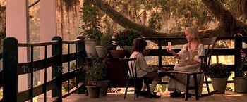 Movie still from “The Patriot” (2000), directed by Roland Emmerich – Two people sitting on chairs on a porch; Wide shot, Over the shoulder angle
