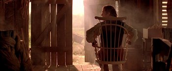 Movie still from “The Patriot” (2000), directed by Roland Emmerich – A man sitting in a rocking chair on the porch of a house; Medium shot, Over the shoulder angle