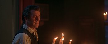 Movie still from “The Patriot” (2000), directed by Roland Emmerich – A man standing in front of some lit candles in the dark; Close Up shot, Low angle