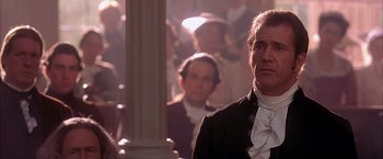 Movie still from “The Patriot” (2000), directed by Roland Emmerich – A man in a suit standing in front of other men; Close Up shot, Over the shoulder angle