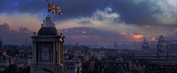 Movie still from “The Patriot” (2000), directed by Roland Emmerich – A view of a british flag flying over a city; Extreme Wide shot, Low angle