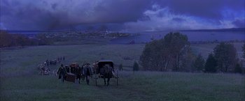 Movie still from “The Patriot” (2000), directed by Roland Emmerich – A group of people riding in a horse drawn carriage on top of a grass covered field; Extreme Wide shot, High angle