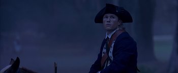 Movie still from “The Patriot” (2000), directed by Roland Emmerich – A man wearing a hat and a tie sitting in a chair; Medium shot, Low angle