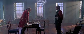 Movie still from “The Patriot” (2000), directed by Roland Emmerich – Two men are standing at a table in front of a window; Wide shot, High angle