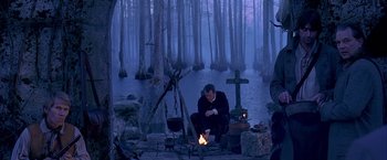 Movie still from “The Patriot” (2000), directed by Roland Emmerich – A man sitting in front of a fire in the middle of the woods; Wide shot, Over the shoulder angle