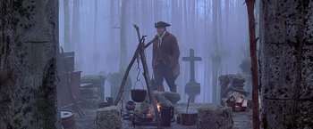 Movie still from “The Patriot” (2000), directed by Roland Emmerich – A man standing in front of an outdoor fire pit; Wide shot, High angle