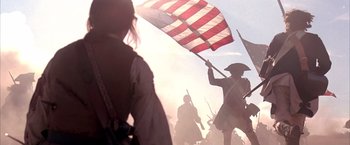 Movie still from “The Patriot” (2000), directed by Roland Emmerich – A group of people holding a flag in a field; Medium shot, Low angle