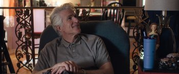 Movie still from “Breaking News in Yuba County” (2021), directed by Tate Taylor – An older man sitting in a chair with his hands clasped together; Close Up shot, Over the shoulder angle