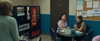 A woman sitting at a table in front of a vending machine