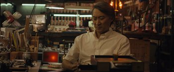 Movie still from “Breaking News in Yuba County” (2021), directed by Tate Taylor – A man sitting at a table in front of a counter; Medium shot, Low angle