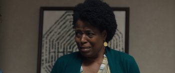 Movie still from “Breaking News in Yuba County” (2021), directed by Tate Taylor – An older black woman wearing a green jacket and yellow earrings; Close Up shot, Over the shoulder angle