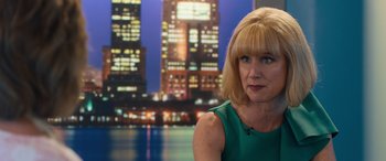 Movie still from “Breaking News in Yuba County” (2021), directed by Tate Taylor – A woman in a green dress in front of a city skyline at night; Close Up shot, Over the shoulder angle