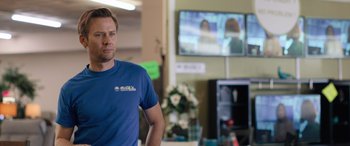 Movie still from “Breaking News in Yuba County” (2021), directed by Tate Taylor – A man standing in front of a tv in a room; Close Up shot, Over the shoulder angle