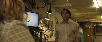 Movie still from “Breaking News in Yuba County” (2021), directed by Tate Taylor – A man standing in front of a computer monitor; Medium shot, Over the shoulder angle