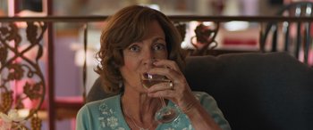 Movie still from “Breaking News in Yuba County” (2021), directed by Tate Taylor – A woman drinking a glass of wine while sitting in a chair; Close Up shot, Over the shoulder angle