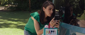A woman looking at her cell phone while holding a gift bag