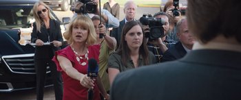 Movie still from “Breaking News in Yuba County” (2021), directed by Tate Taylor – A group of people with cameras and microphones gathered together; Close Up shot, Over the shoulder angle