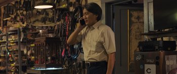 Movie still from “Breaking News in Yuba County” (2021), directed by Tate Taylor – A man talking on a cell phone while standing in a room; Medium shot, Low angle