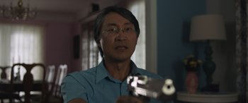 Movie still from “Breaking News in Yuba County” (2021), directed by Tate Taylor – A man holding a gun while wearing glasses; Close Up shot, Over the shoulder angle