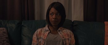 Movie still from “Breaking News in Yuba County” (2021), directed by Tate Taylor – A woman sitting on a couch wearing a plaid shirt; Close Up shot, Over the shoulder angle