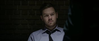 Movie still from “Broken” (2021), directed by Patrick Phillips – A man in a dress shirt and a tie looking at the camera; Close Up shot, Over the shoulder angle