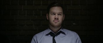 Movie still from “Broken” (2021), directed by Patrick Phillips – A person wearing a shirt and a tie; Close Up shot, Low angle