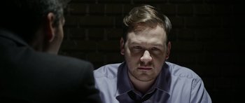 Movie still from “Broken” (2021), directed by Patrick Phillips – A person wearing a shirt and tie; Close Up shot, Over the shoulder angle