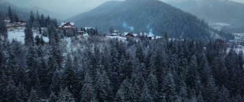 Movie still from “Broken” (2021), directed by Patrick Phillips – A view of a snowy forest with a mountain in the background; Extreme Wide shot, High angle