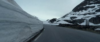 Movie still from “Broken” (2021), directed by Patrick Phillips – A road with snow on the side of a mountain; Extreme Wide shot, Low angle