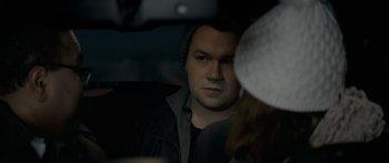 Movie still from “Broken” (2021), directed by Patrick Phillips – A man with a hat is sitting in the back of a car; Close Up shot, Over the shoulder angle